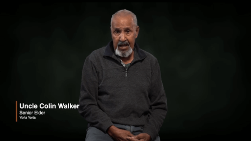 Uncle Colin Walker talking about coming together to care for Country in-front of a black background