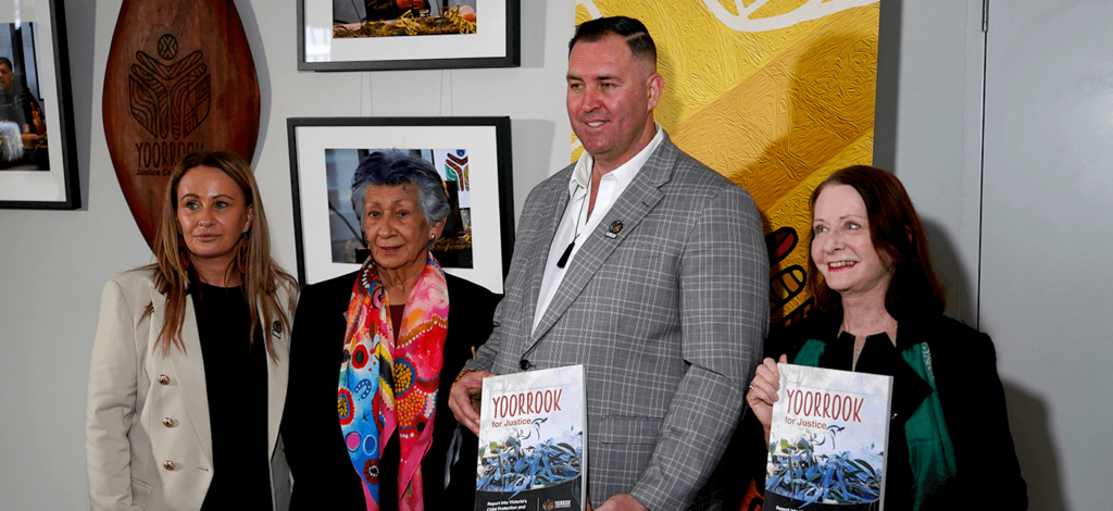 Yoorrook Commissioners presenting the Yoorrook for justice report in their hands with the Yoorrook shield behind them
