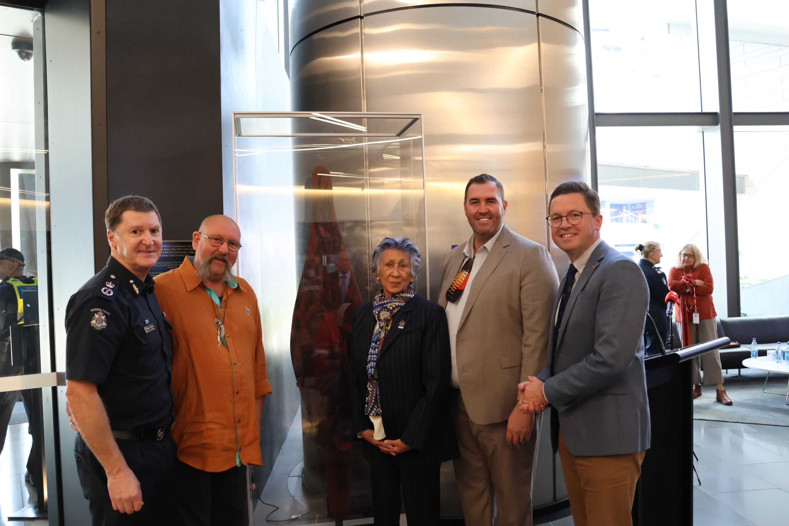 Chief Commissioner of Victoria Police Shane Patten, artist Uncle Mick Harding, Yoorrook Chair Eleanor Bourke, Yoorrook Deputy Chair Travis Lovett, Minister for Police Anthony Carbines MP posing with the Yoorrook shield at the Victoria Police headquarters